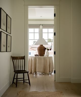 neutral hallway with a runner rug and view into entryway with circle table