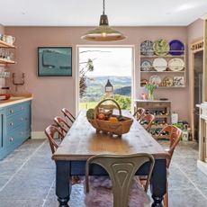 country kitchen with farmhouse table and metal chairs in centre of the room with blue painted cabinetry