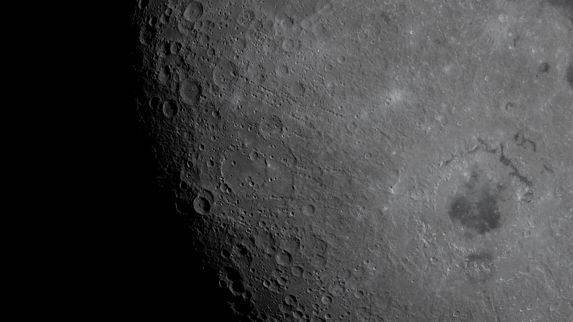 a closeup of the moon's surface, showing a large, dark basin