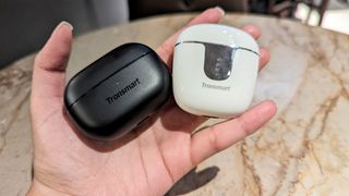 Tronsmart Onyx Ace Pro wireless earbuds and Tronsmart Onyx Pure earbuds inside their cases held in one hand