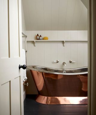 Neutral attic bathroom with copper roll top bath designed by Emma Milne