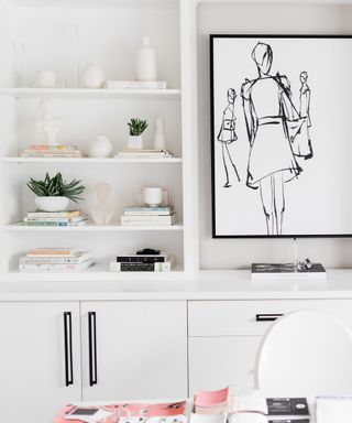 An all-white bookshelf with black-and-white artwork, small plants and white vases