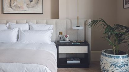 Beige bedroom with wrap around headboard and houseplant in pot