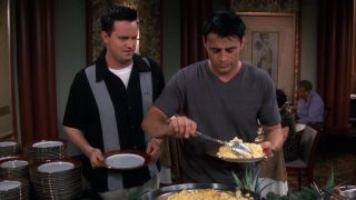 Joey (Matt LeBlanc) piles scrambled eggs onto his plate at the buffet as Chandler (Matthew Perry) watches on Friends "The One After Vegas."