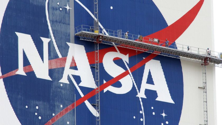 workers on scaffolding paint a nasa logo on a massive white building