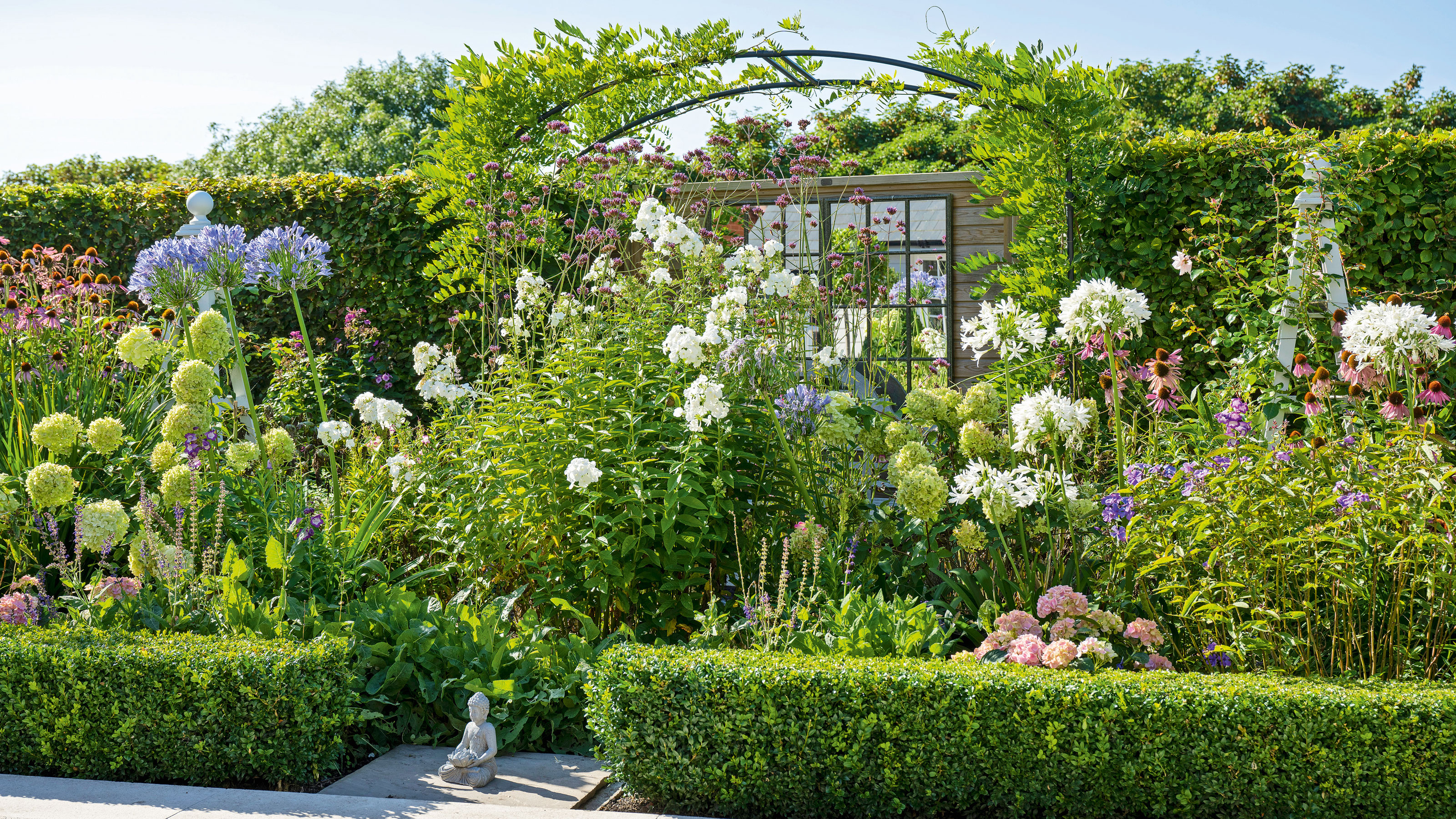 Garden border with flowers and a wisteria arch