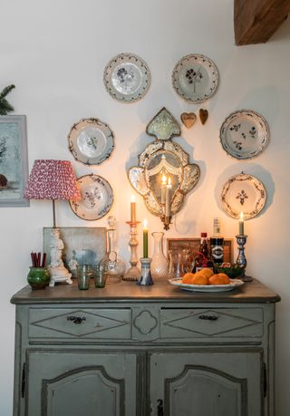 gallery wall of vintage plates arranged round a mirrored candle sconce