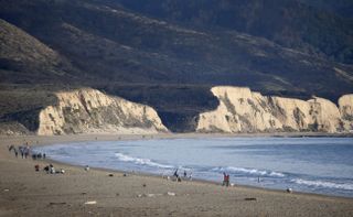 People walk along the shoreline at Limantour Beach in Northern California