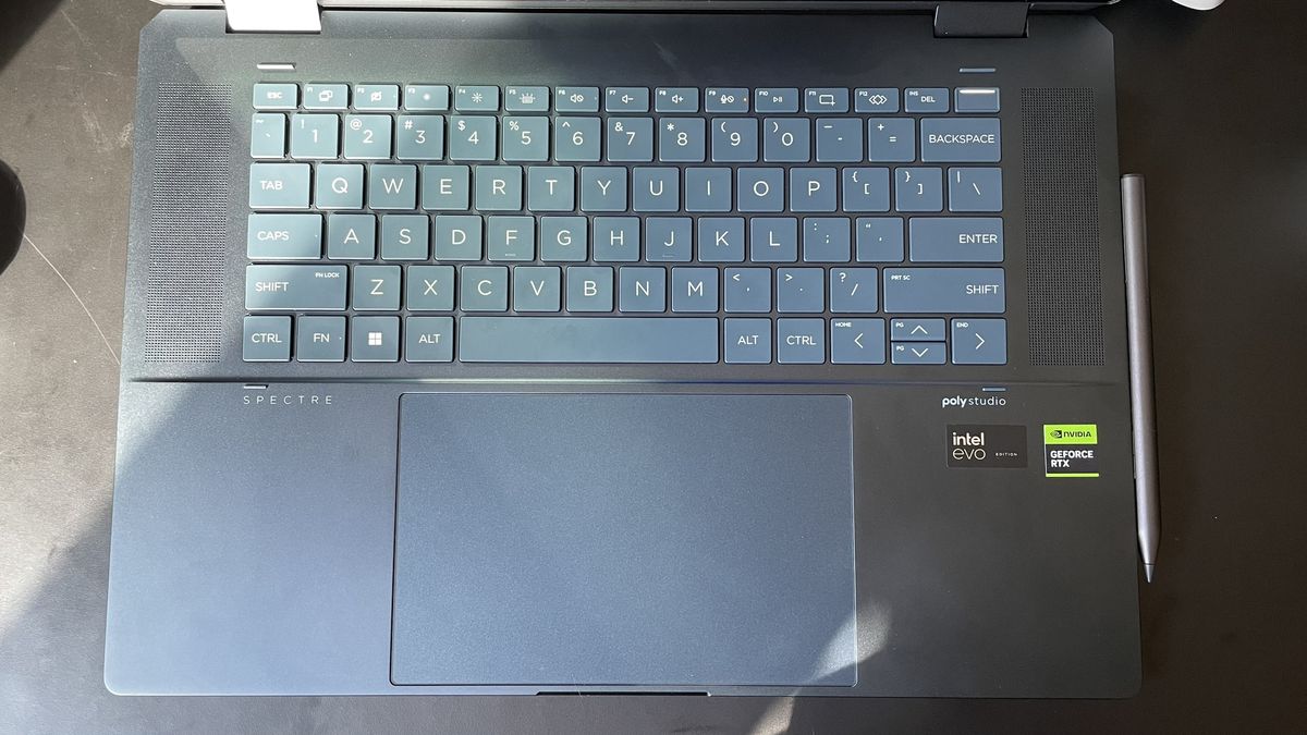 A close up of a dark-colored laptops keyboard and trackpad on top of a black surface.
