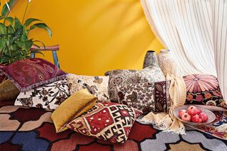 An assortment of patterned scatter cushions against a mustard yellow background