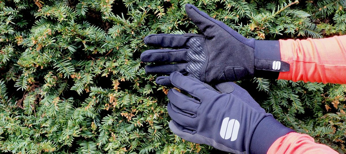 Off-road cycling gloves in front of a hedge