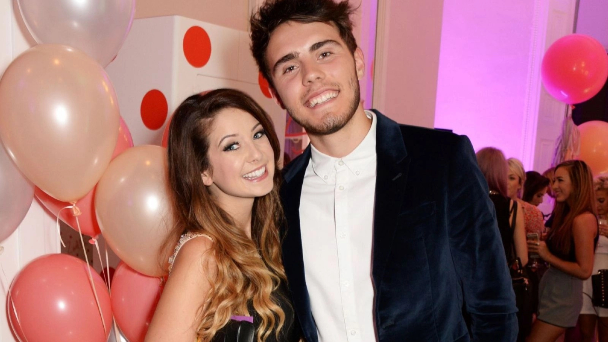 male and female stood in party with balloons behind them