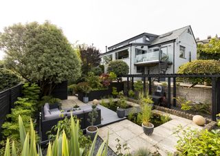 modern patio and garden space with black pergola and pond