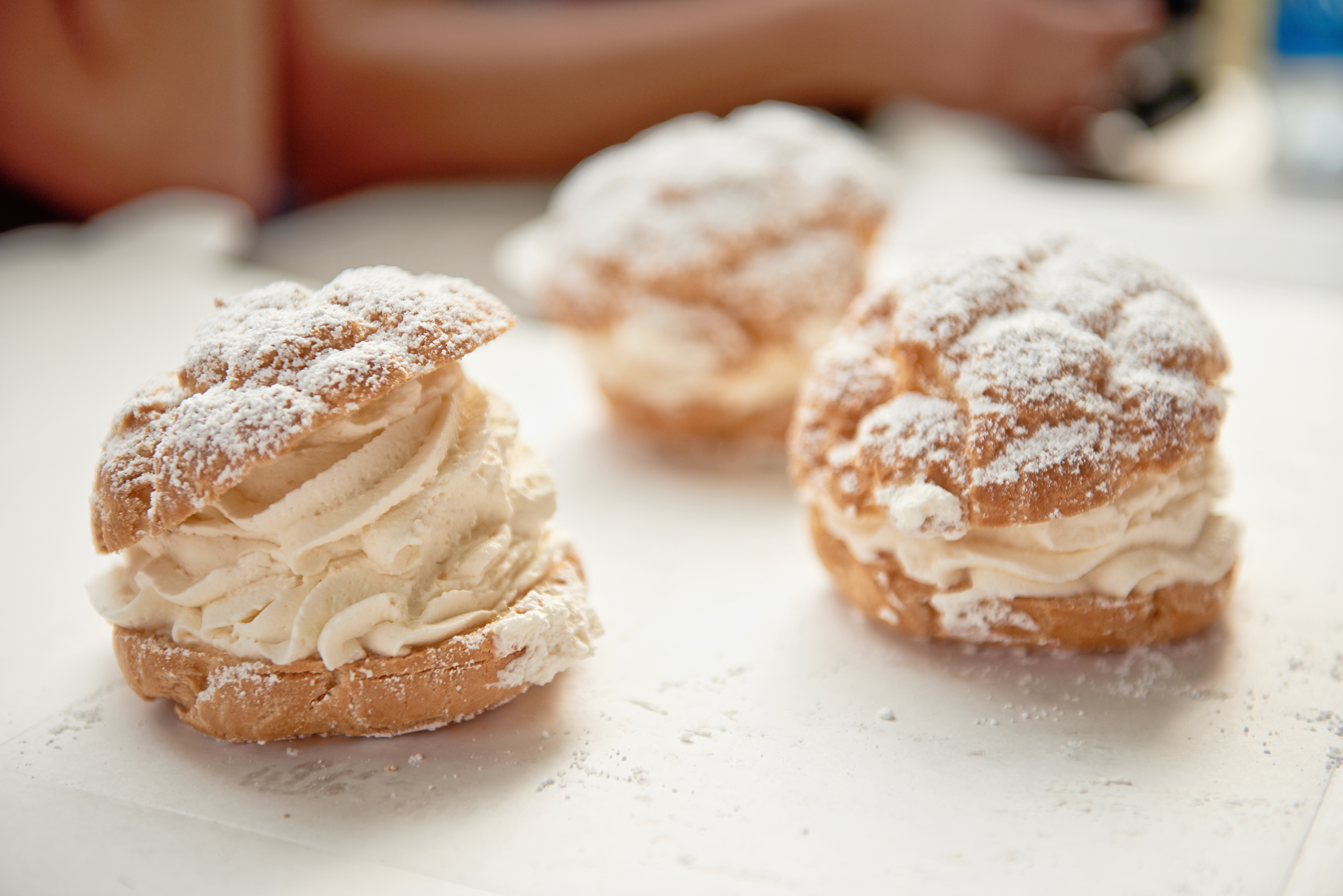 Three cream puffs on a white surface