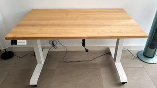 Desky Dual Hardwood standing desk against a wall