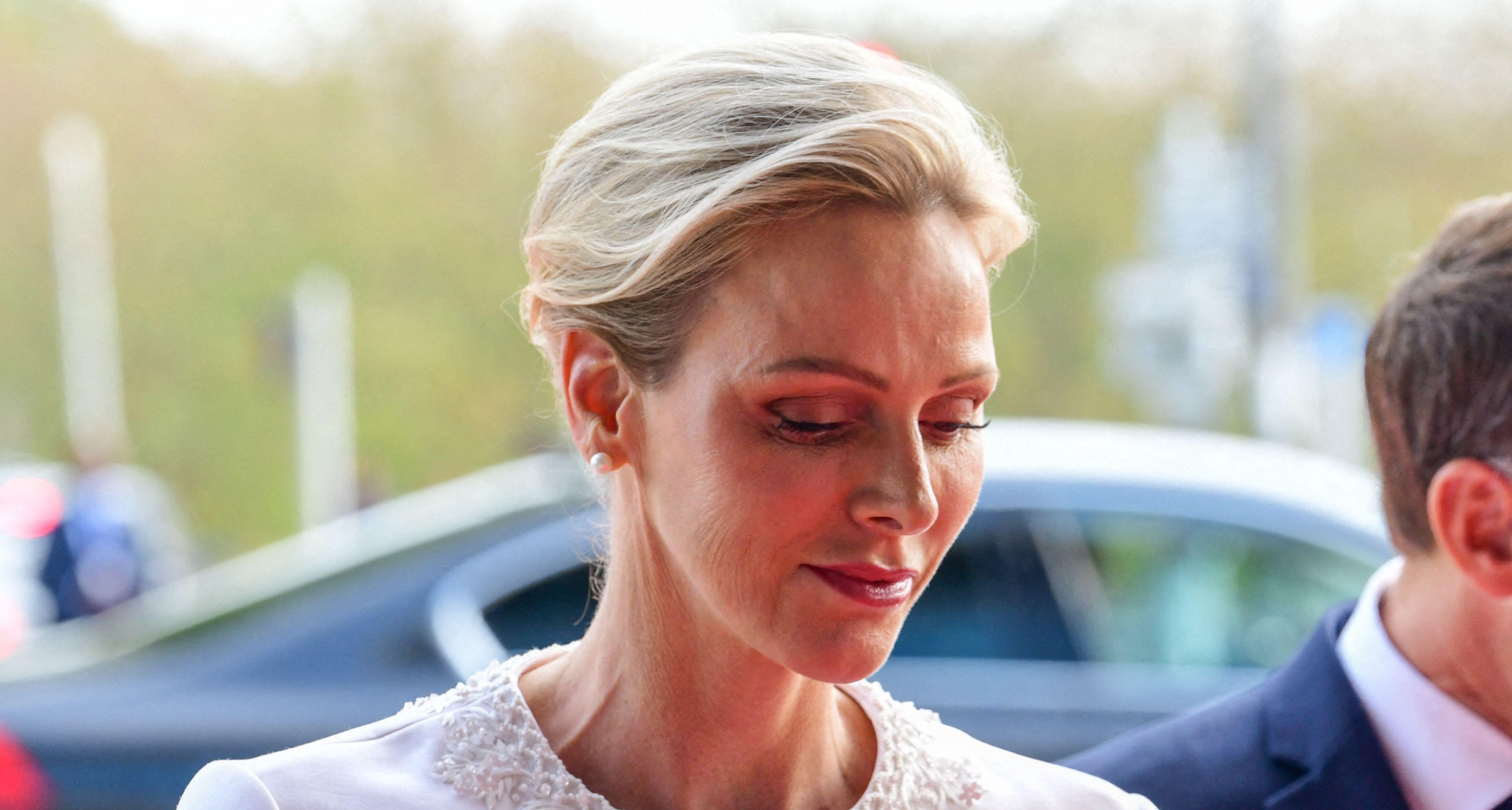 Princess charlene wearing a white jacket and looking down