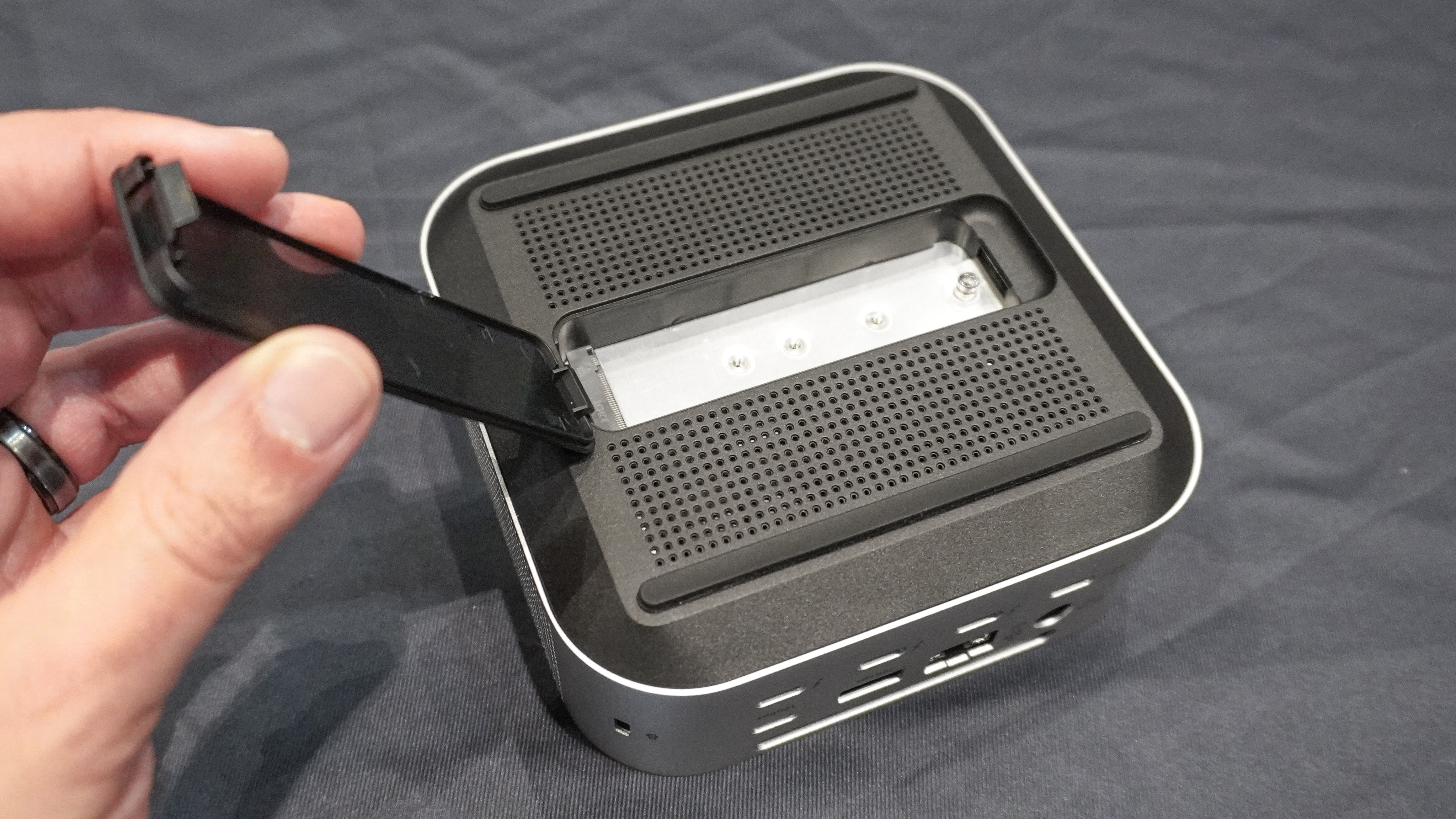 A person opening the lid of the SSD enclosure on the bottom of the Satechi CubeDock