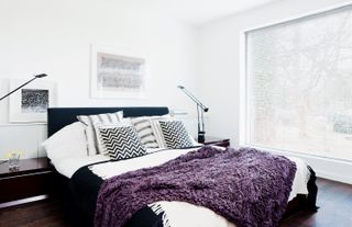 monochrome bed in a white bedroom with purple throw