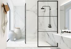 Shower design for a small bathroom in a white marble scheme with black metal work.
