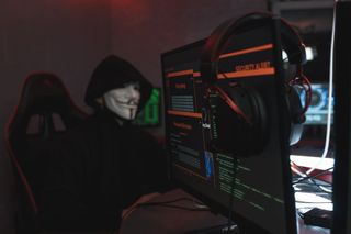 DDoS scenario: Person in Black Hoodie Hacking a Computer System