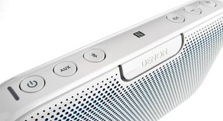 The aux selector, Bluetooth initiator, NFC sensor and volume buttons sit above an 'on' light around the Denon logo