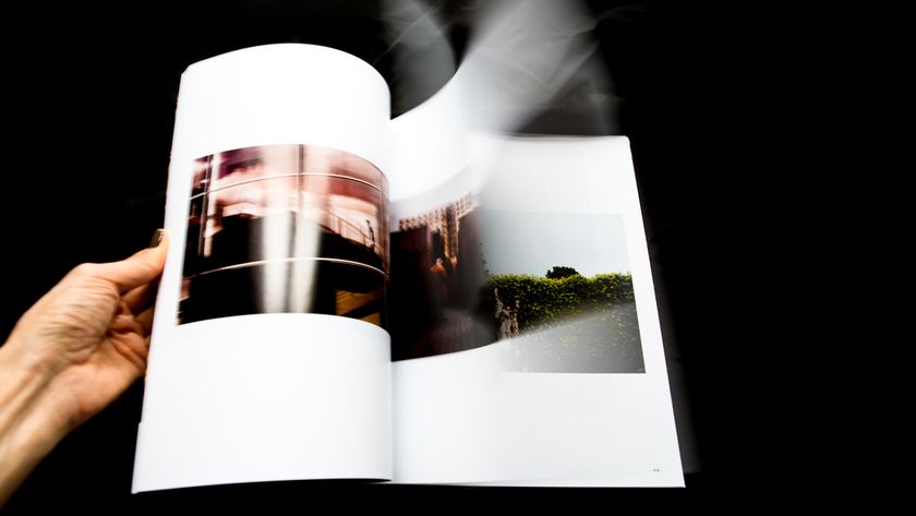 A hand flipping through a photo book with blurred motion on a black background