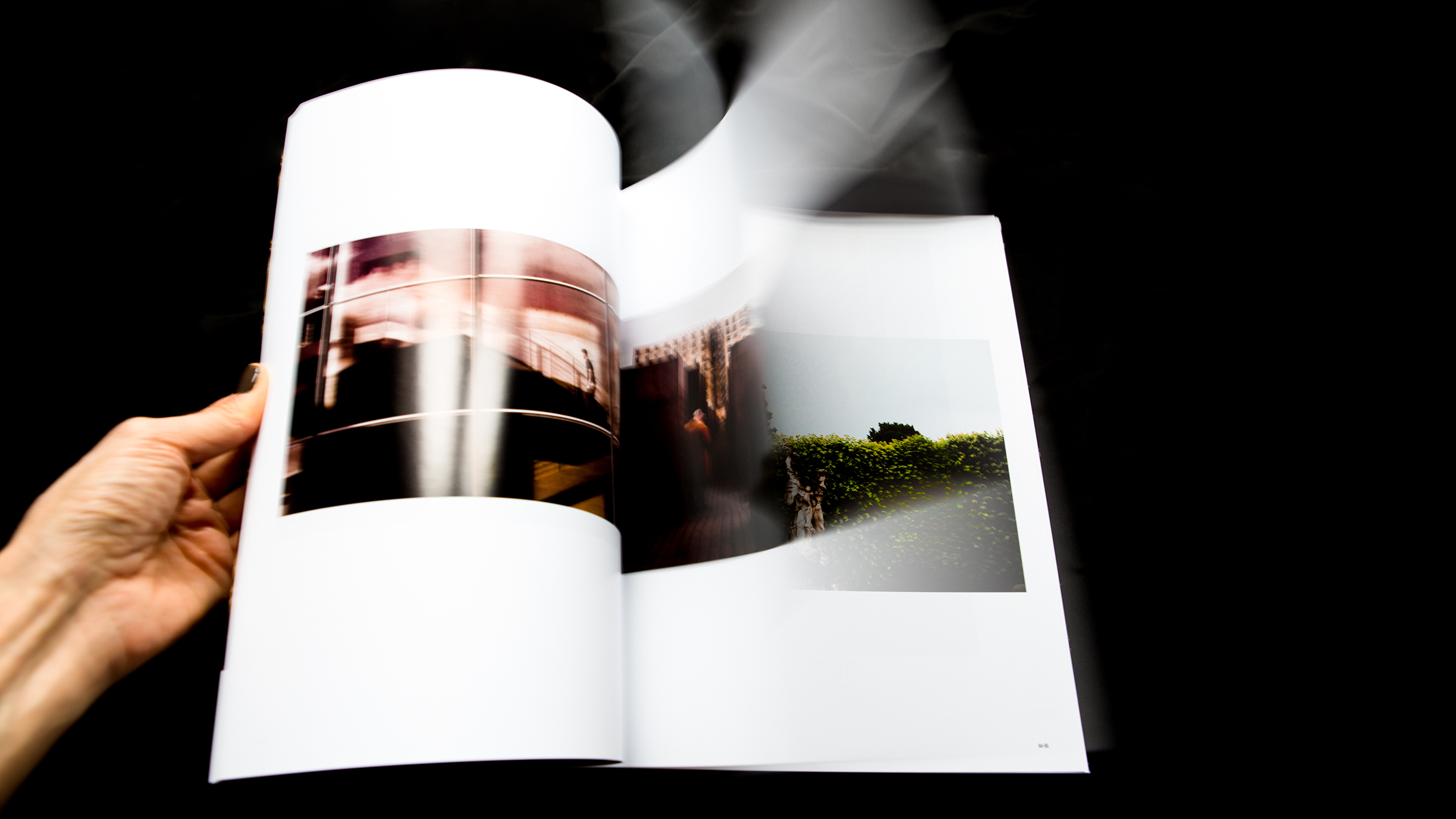 A hand flipping through a photo book with blurred motion on a black background