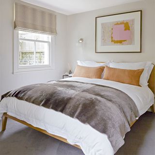 guest bedroom with white wall and pillows on bed with cosy blanket