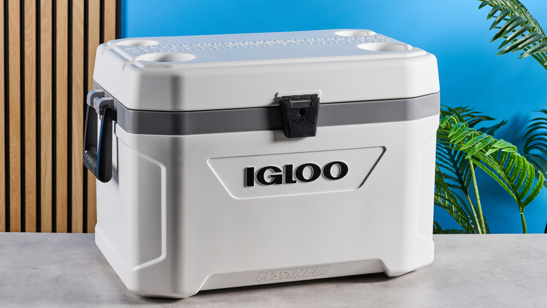 the igloo marine ultra 54 cooler in white with a latch, handles, a big igloo logo on the front and with a fish ruler and drink holders