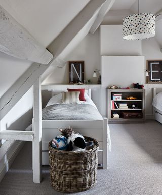 A shared boys' attic bedroom with minimalist-inspired boys' bedroom ideas, white walls and wicker basket storage.
