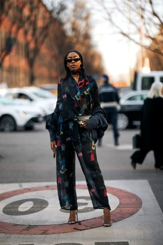 A woman in Milan Fashion Week's Fall 2025 street style in a white, red, and blue floral dress with a colorful orange cardigan