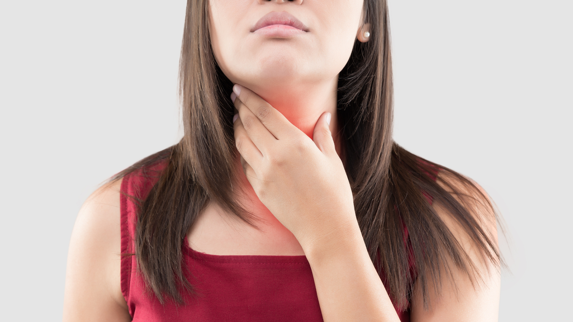 A close up of a woman's throat with her dark hair around it and her hand touching it