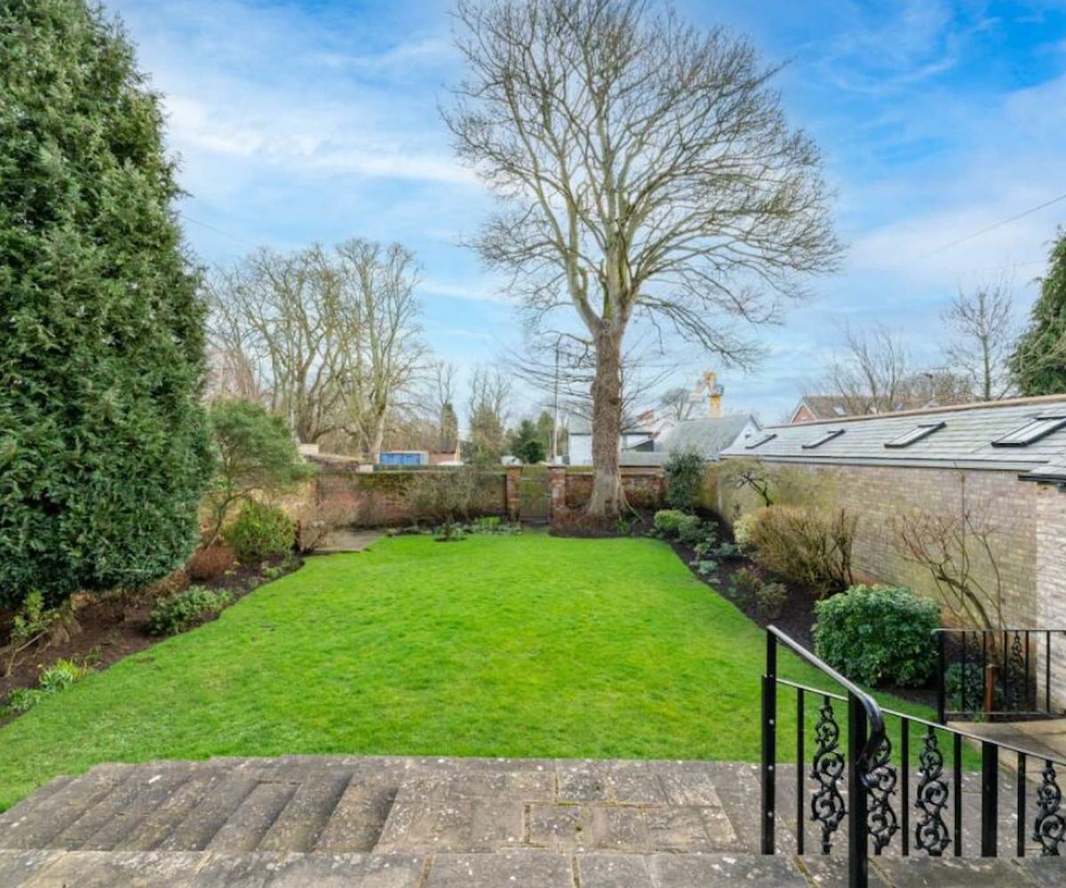 A rear garden with a tree at the bottom with a Victorian handrail