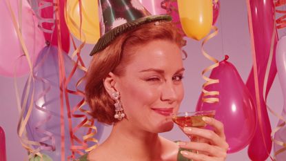 UNITED STATES - CIRCA 1960s: Woman at party, wearing party hat and winking, holding glass of wine.