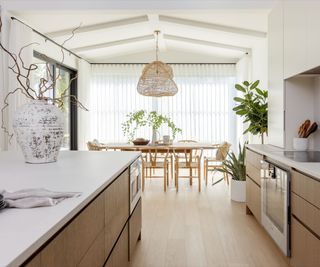 A wood and white kitchen with a sculptural organic light above the dining table