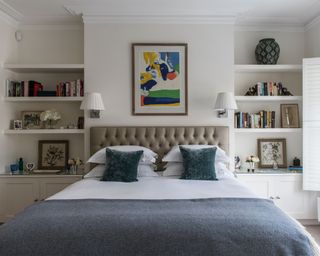 Bedroom wall lighting ideas with two small white lamps above a double bed with a blue throw and green velvet cushions