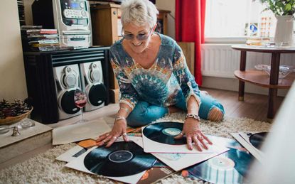Woman looking through a stack of vinyl records on the floor.