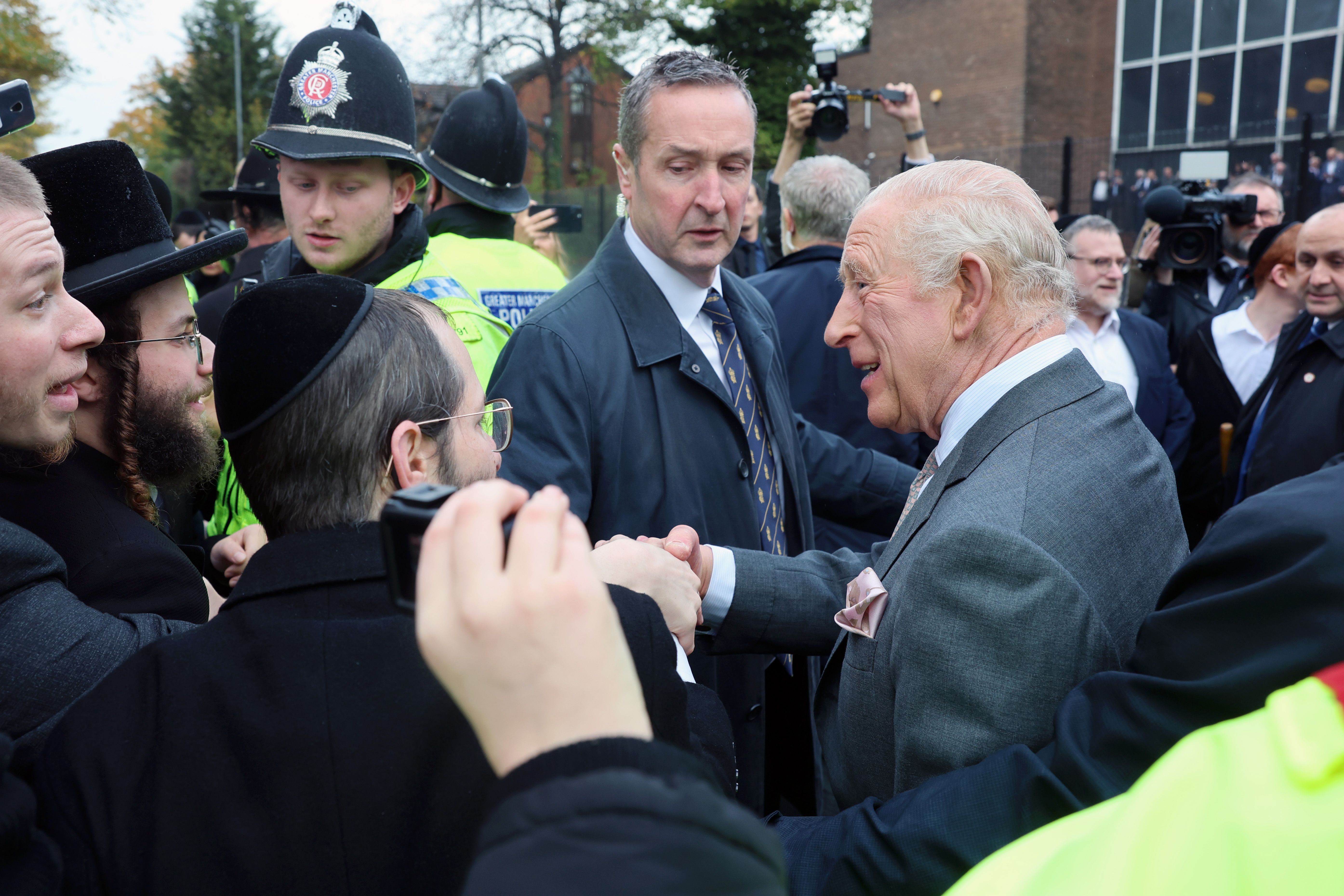 King Charles shaking hands with men outside a synagogue