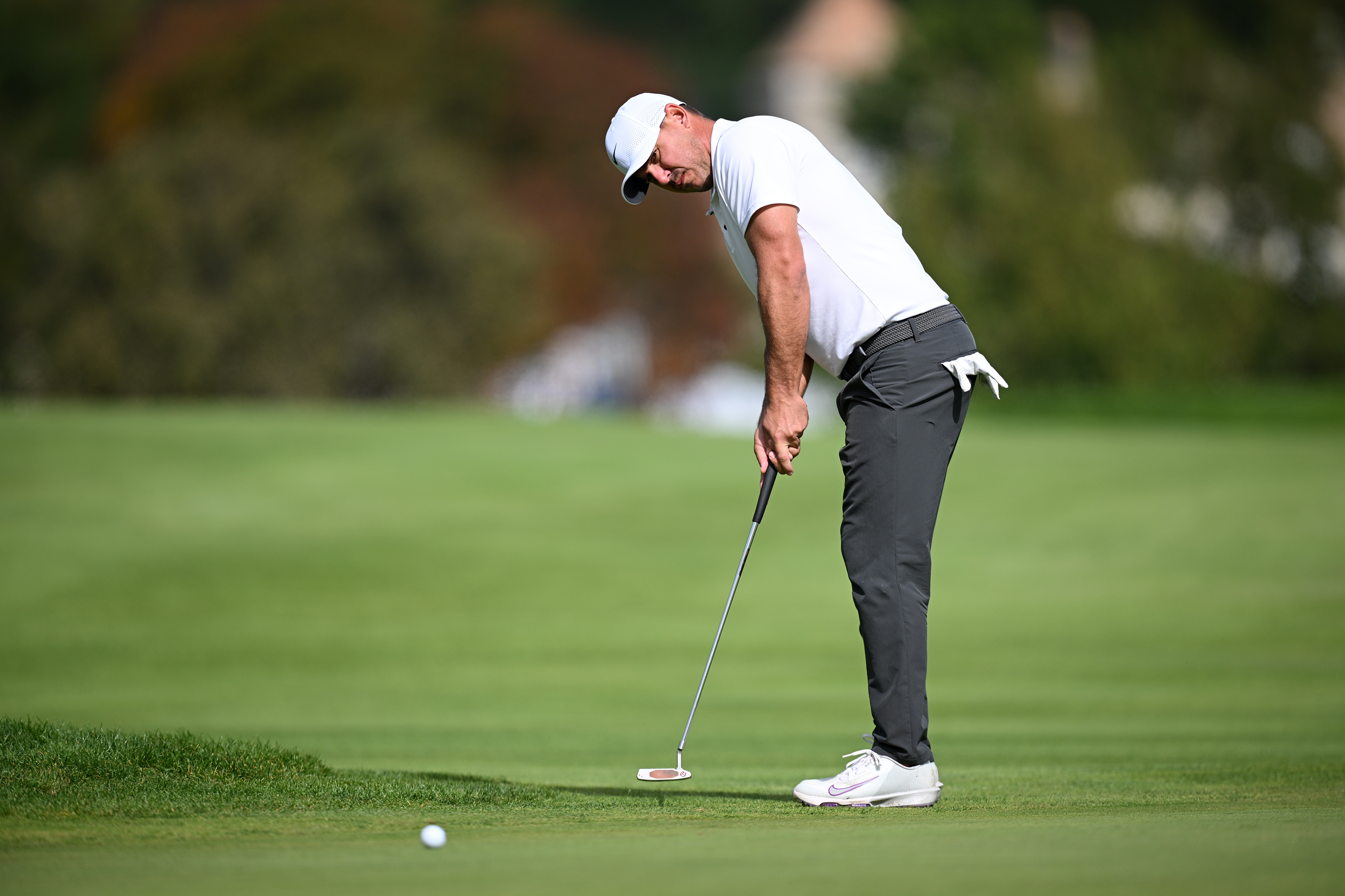 Brooks Koepka hits a putt on the green