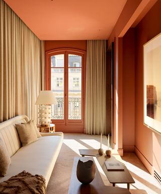 orange living room with cream sofa and curtains
