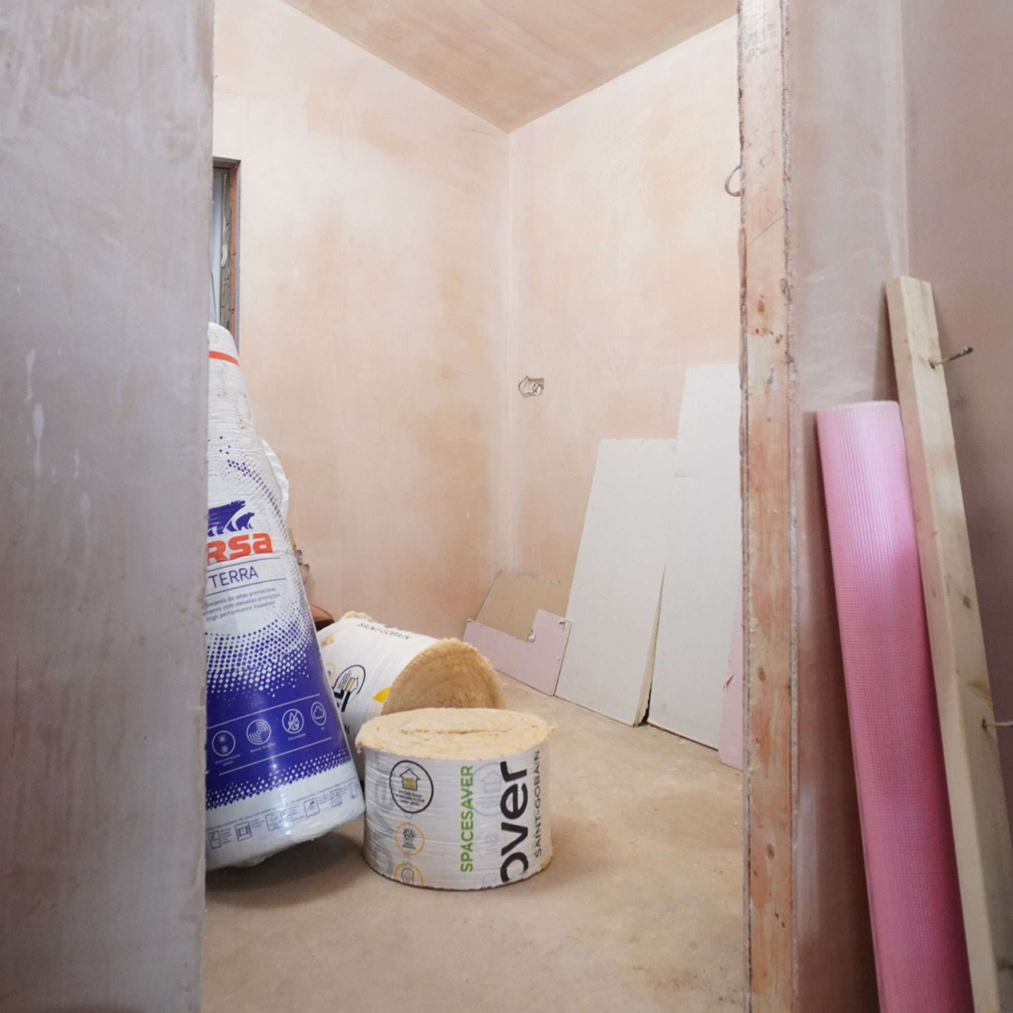 Bags of insulation in room with wood panels leaning against plastered walls
