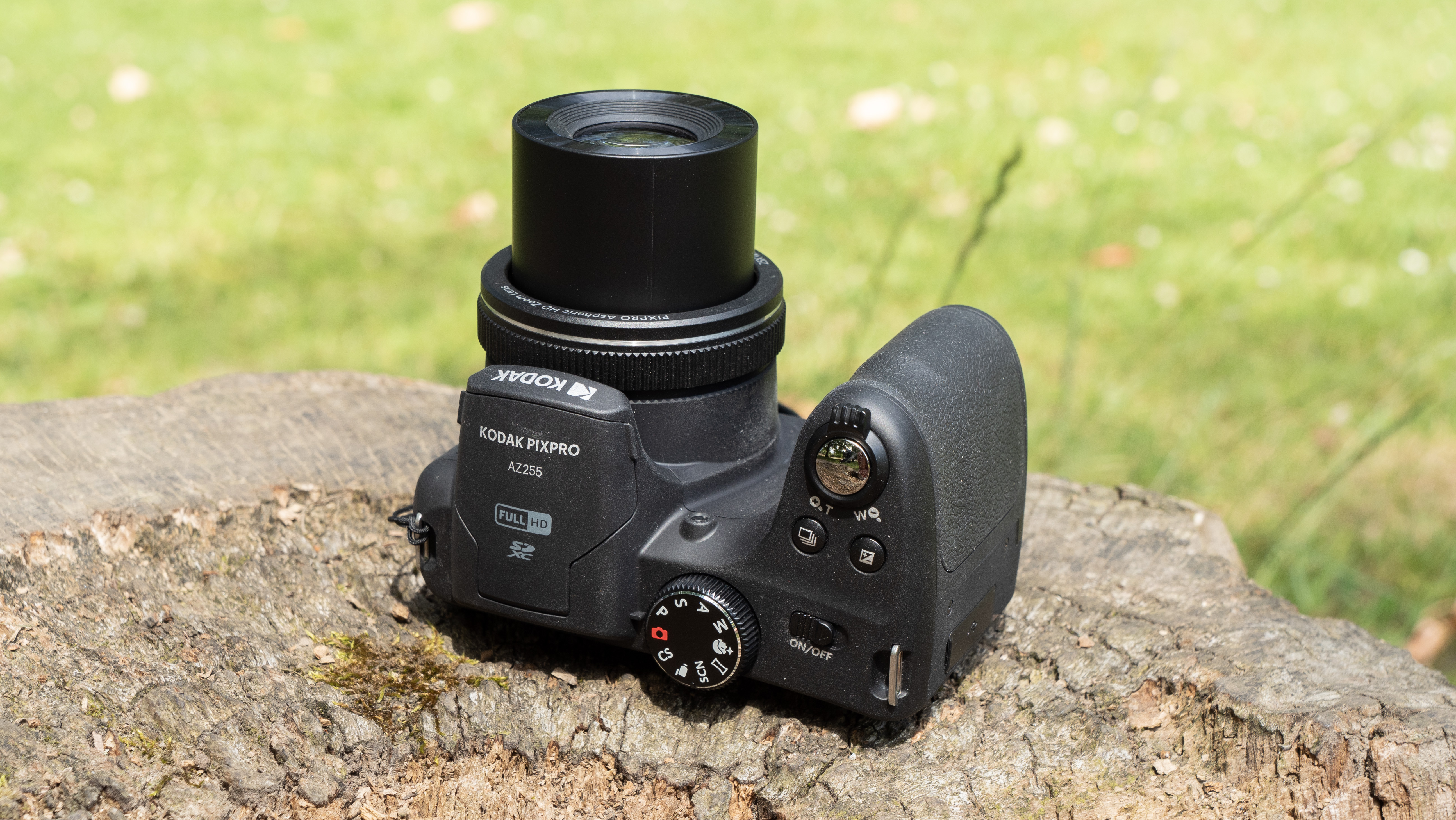 Kodak PixPro AZ255 digital camera in black on a stone surface in front of a green background outside