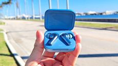 Listing image for best cheap wireless earbuds showing OnePlus Buds 3 in charging case held in hand in outdoors 