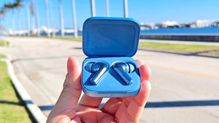 Listing image for best cheap wireless earbuds showing OnePlus Buds 3 in charging case held in hand in outdoors 