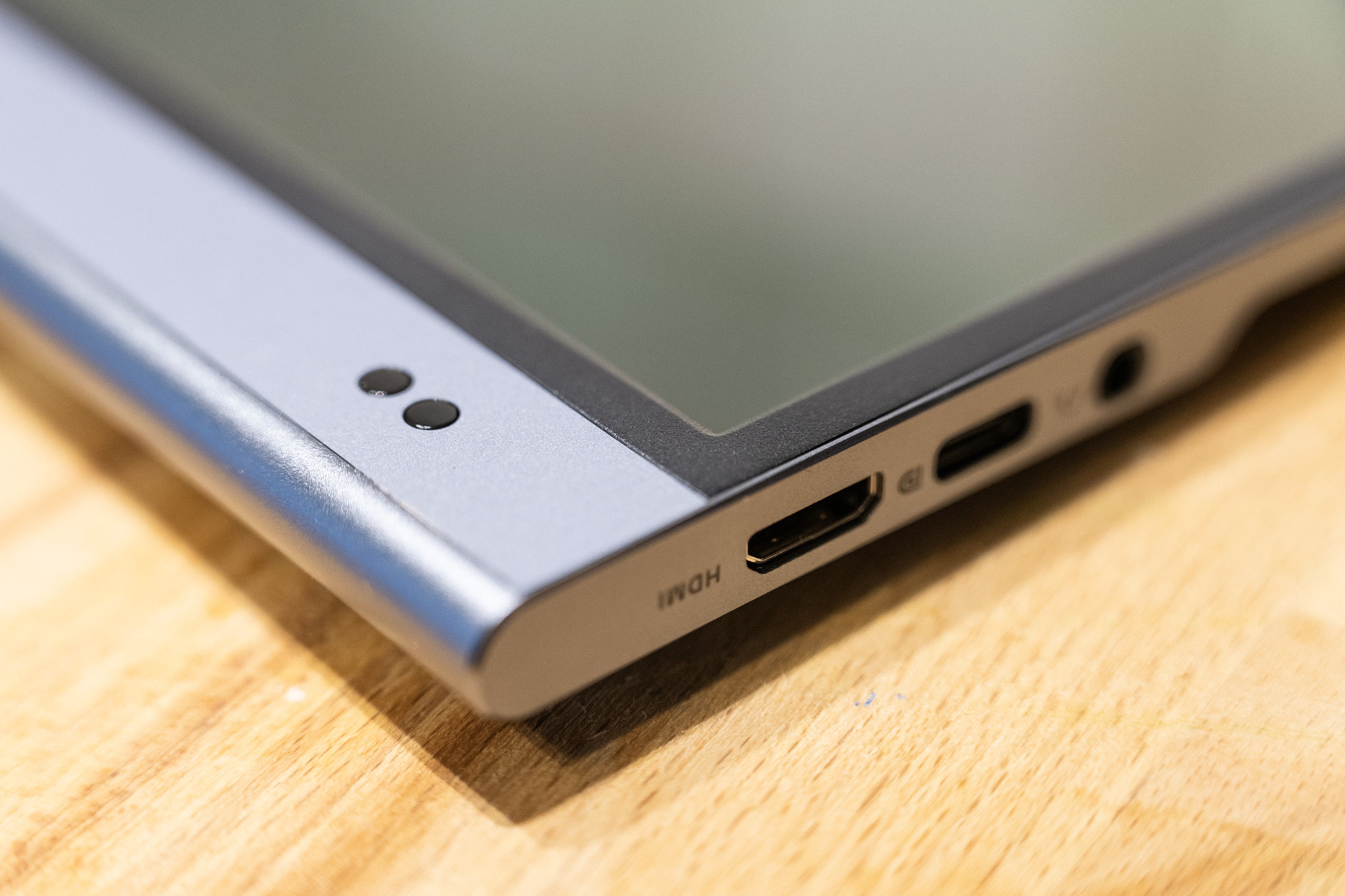 A black and silver ASUS ZenScreen MQ16AH portable monitor on a wooden brown desk