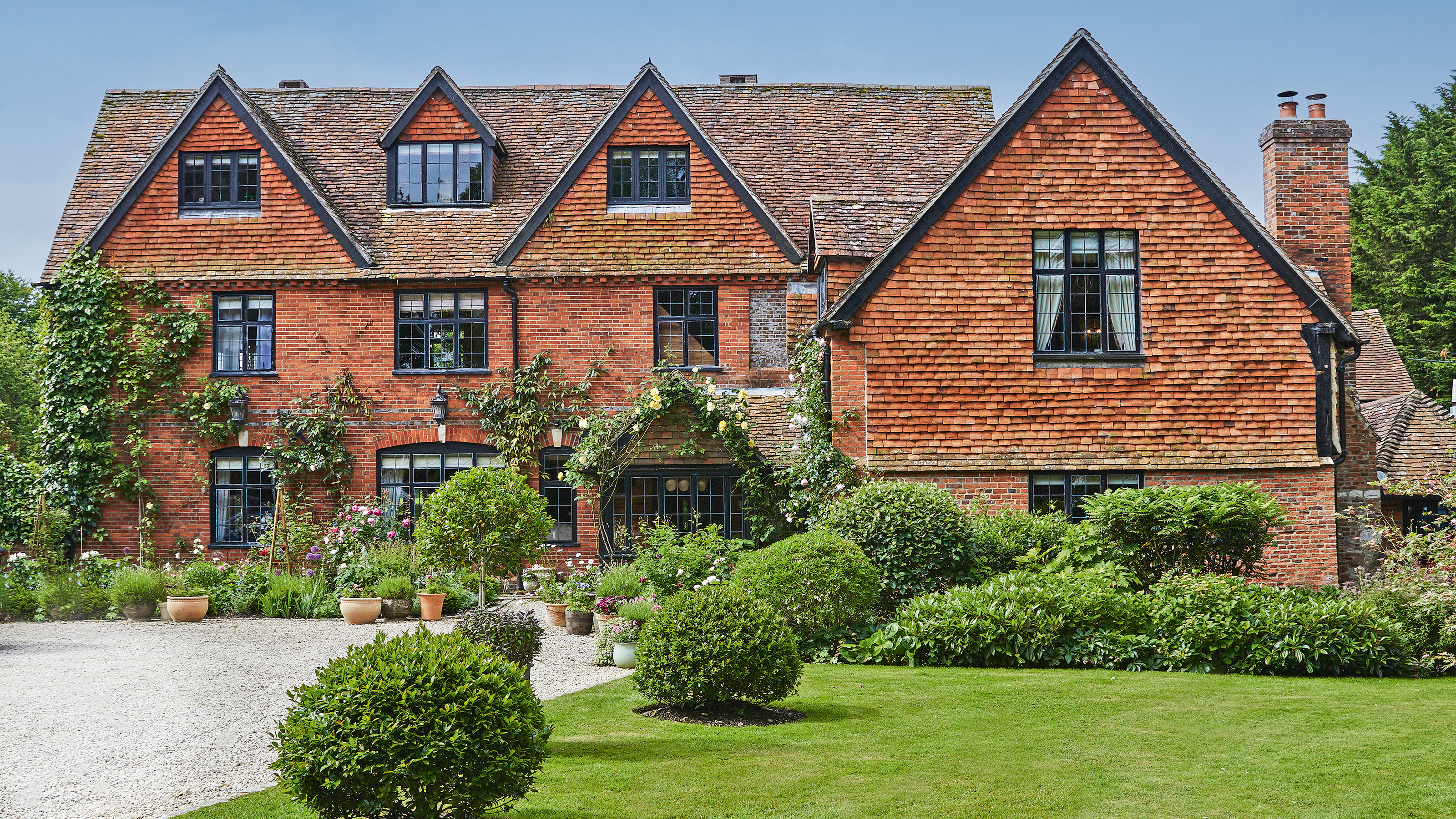 exterior of a medieval manor with leaded windows and climbing roses