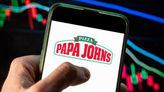 The logo of Papa John's is shown on a phone held in a person's hand, with a digital chart made of red, green and blue lines shown in the background
