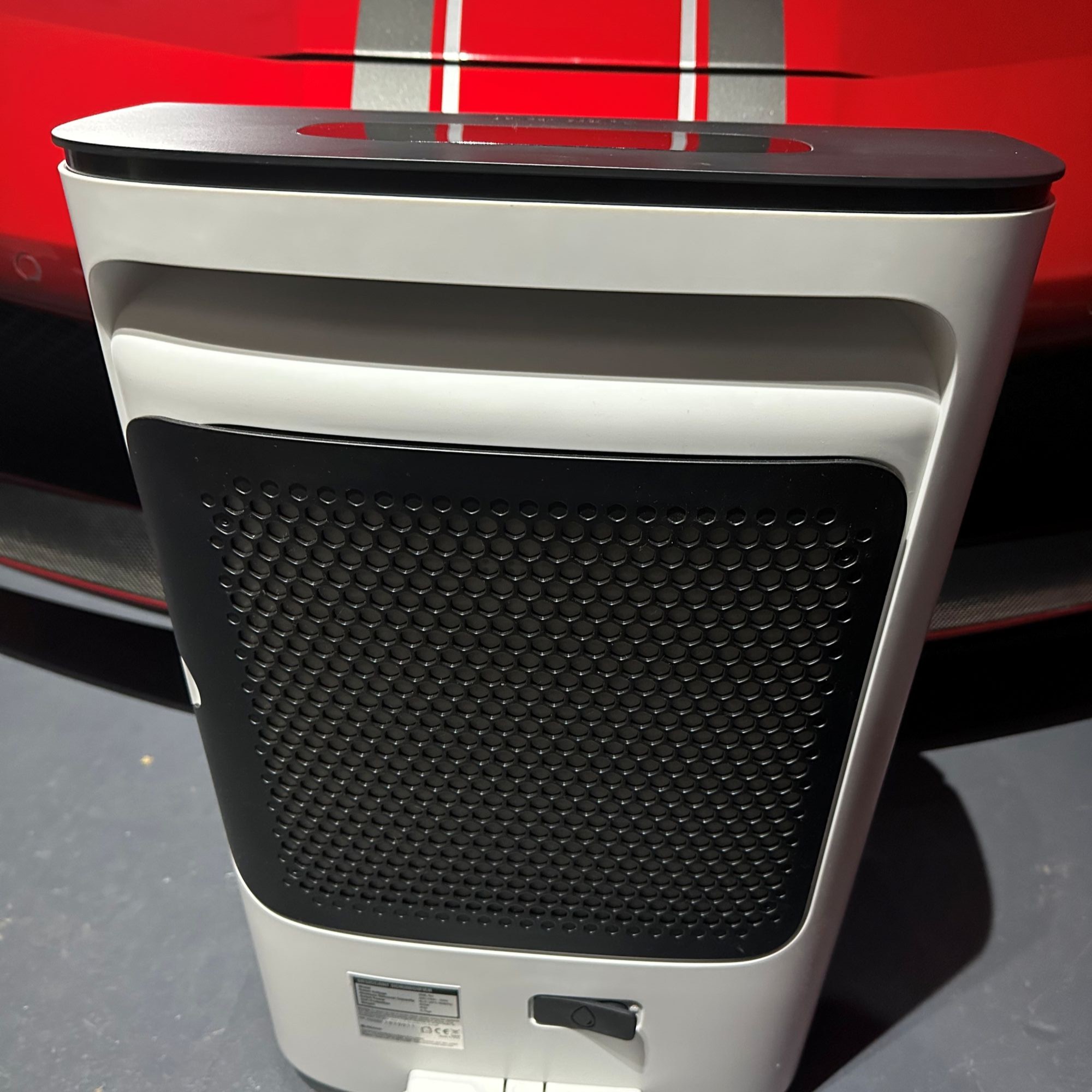 The black back filter of the DD8L dehumidifier in front of a red super car with silver stripes on it
