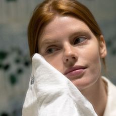 woman rinsing her face with a face cloth