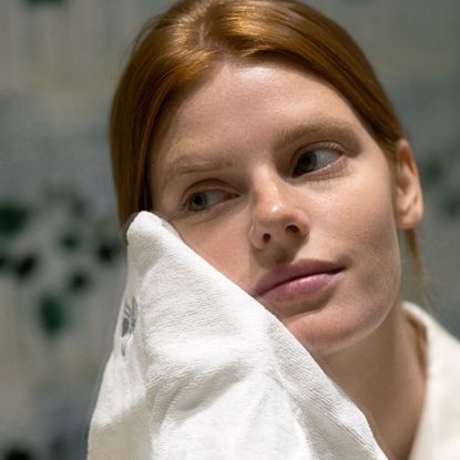 woman rinsing her face with a face cloth